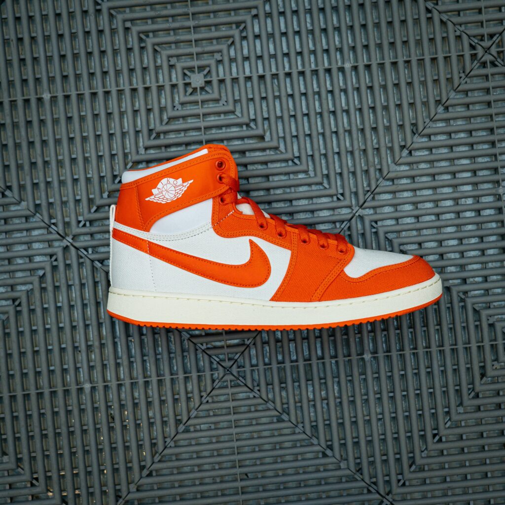 Detailed close-up of a vibrant orange and white sneaker on patterned surface.