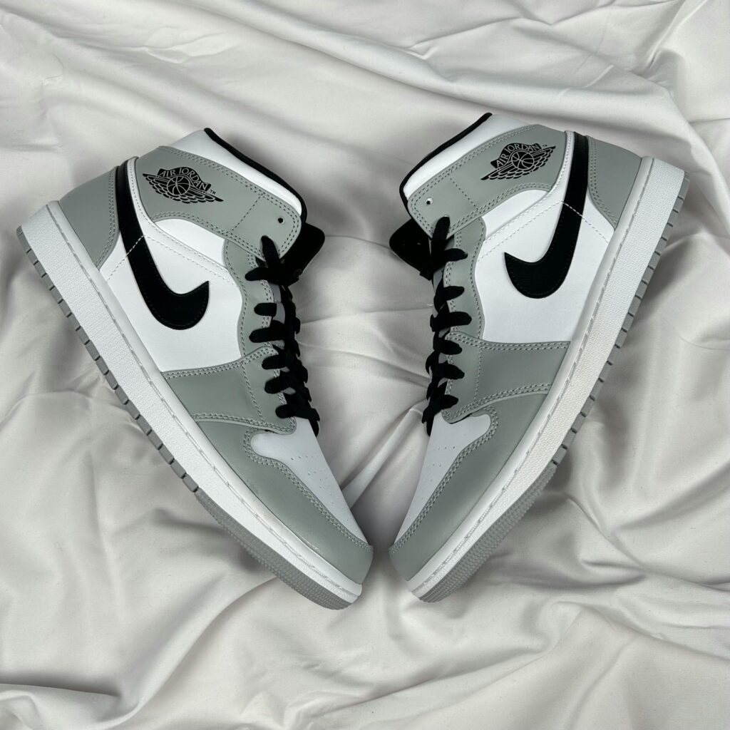 Stylish gray and white high-top sneakers laid on soft fabric background.